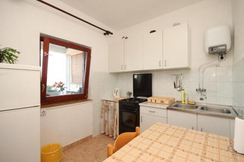 uma cozinha com armários brancos, uma mesa e uma janela em Apartments by the sea Luka, Dugi otok - 8151 em Luka