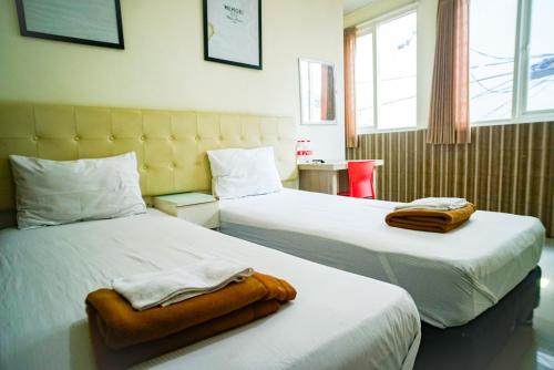 pokój hotelowy z 2 łóżkami i ręcznikami w obiekcie Hoki Homestay Mitra RedDoorz near Rumah Sakit Dr Soetomo Surabaya w mieście Karangmendjangan