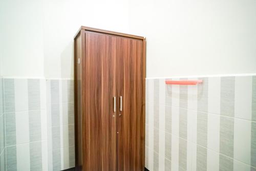 drewniane drzwi w łazience ze ścianą wyłożoną kafelkami w obiekcie Hoki Homestay Mitra RedDoorz near Rumah Sakit Dr Soetomo Surabaya w mieście Karangmendjangan