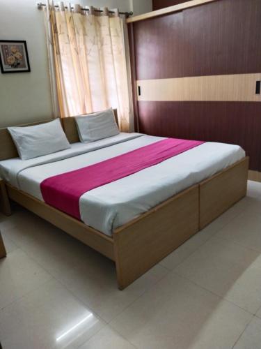 Schlafzimmer mit einem großen Bett mit einem Kopfteil aus Holz in der Unterkunft HOTEL SLN Homes in Bangalore