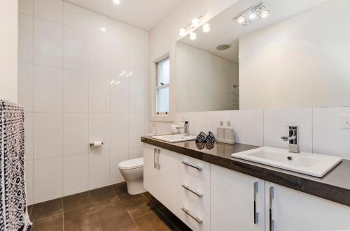 W łazience znajduje się umywalka, toaleta i lustro. w obiekcie Dianas Place w mieście Warrnambool
