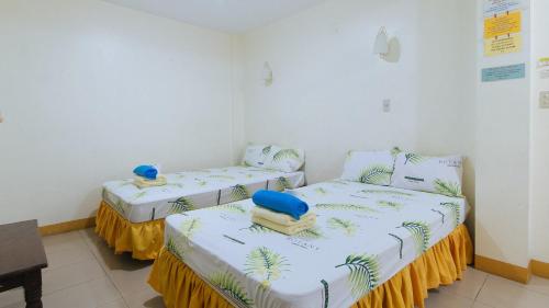 two twin beds in a room with a table at Golden Sunrise Hotel I by RedDoorz 