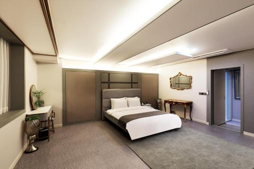 1 dormitorio con 1 cama blanca grande y espejo en Buan Tourist Hotel en Buan