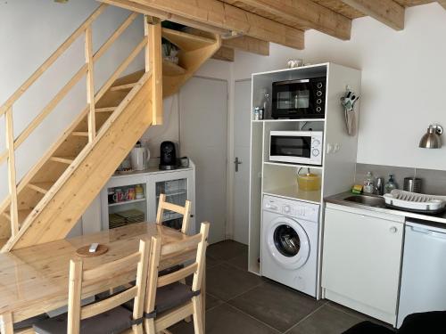 une cuisine avec une table, un escalier et un lave-linge dans l'établissement Petit Fare Rochois avec mezzanine, à La Roche-des-Arnauds
