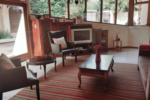 sala de estar con sofá, sillas y TV en Somona Guest House, en Johannesburgo