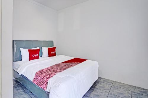 Bett mit roten Kissen auf einem Zimmer in der Unterkunft OYO LIFE 91594 Bungah Residence Syariah in Gresik
