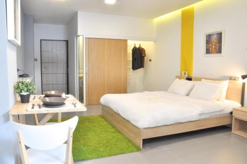 a bedroom with a large white bed and a table at A23 residence in Ban Na Song