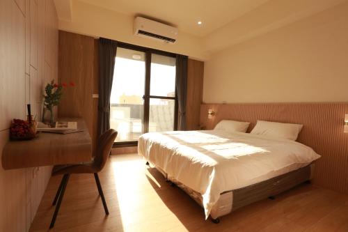 a bedroom with a bed and a desk and a window at Lin House in Checheng