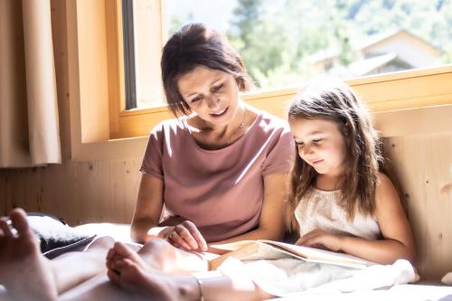 a woman and a little girl reading a book at Wasserfall Apartments Mellau in Mellau