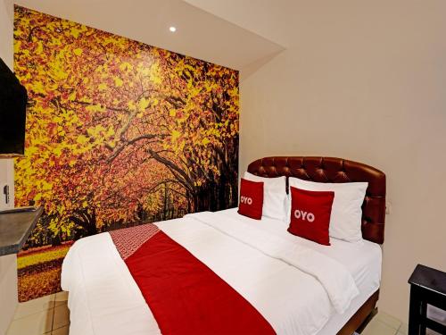 a bedroom with a bed with a painting on the wall at SUPER OYO 91618 Hotel Nawangwulan in Blitar