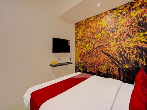 a bedroom with a bed and a painting on the wall at Hotel O Nawangwulan in Blitar