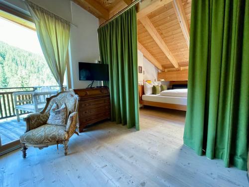 - une chambre avec un lit, une chaise et une télévision dans l'établissement Apartments DA LA VEDLA Flats, à San Cassiano