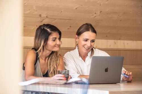 two women sitting at a table with a laptop at Wasserfall Apartments Mellau in Mellau