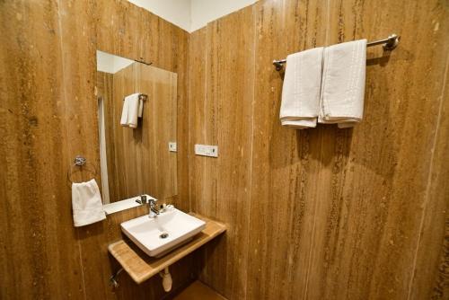 a bathroom with a sink and a mirror and towels at The Bheemgarh in Jaisalmer