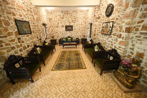 a living room with chairs and a stone wall at ClarksInn Suites Ranthambhore in Sawāi Mādhopur