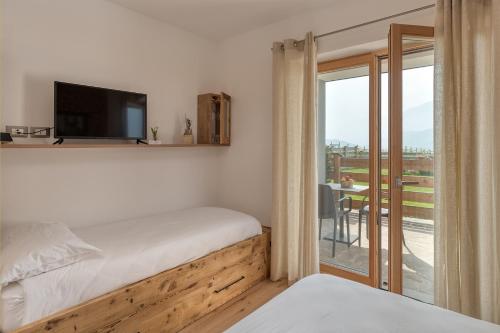 a bedroom with a bed and a tv and a balcony at Agritur Maso Librar in Trento