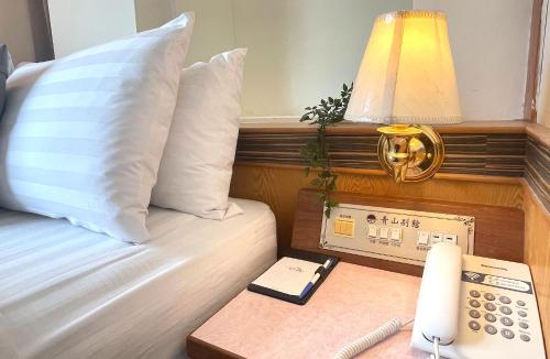 a room with a bed with a telephone and a lamp at Chinshan Villa in Zhongzheng