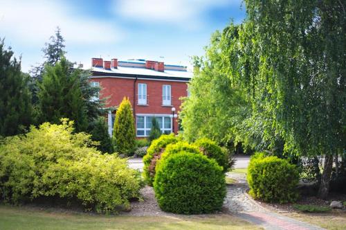 a red brick house with bushes in front of it at Hotel Manhatan in Zygry