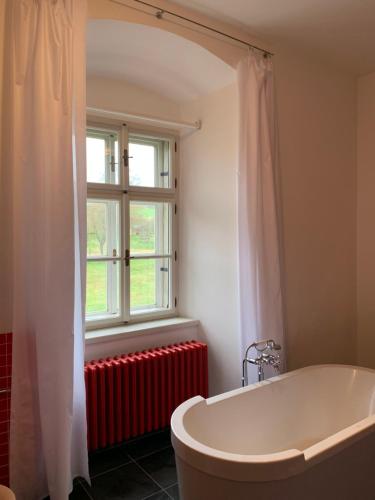 a bathroom with a tub and a window and a red radiator at Zámeček Ostrov in Ostrov