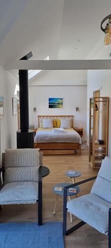 a bedroom with a bed and two chairs at The Brookhouse. Cheerful tiny house with Seaview. in Ilfracombe