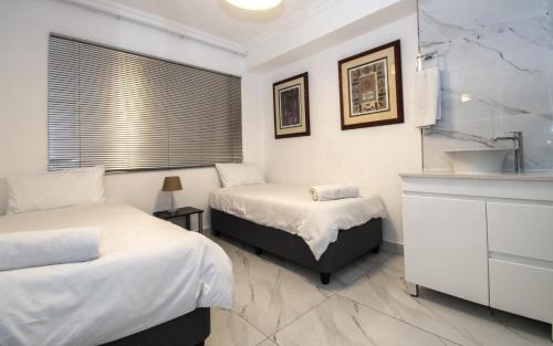 two beds in a room with a sink and a bathroom at 8 Bronze Beach Umhlanga Rocks in Durban