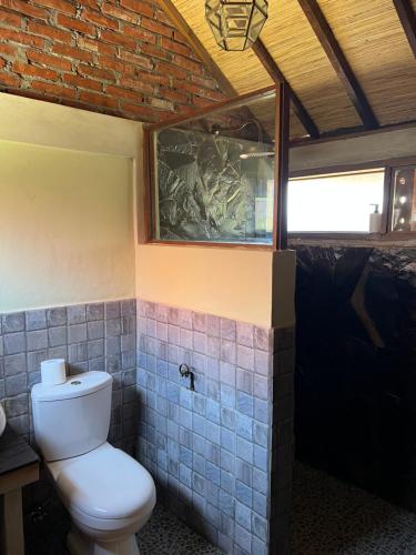 a bathroom with a toilet and a brick wall at PINOKKIO B&B Restaurant in Jimbaran