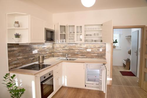 una cocina con armarios blancos y fregadero en Mikulov Apartments - Apartmán Radka en Mikulov