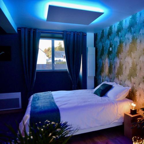 een slaapkamer met een bed met een blauw licht bij L'Evasion chambre LAOS avec Jacuzzi privatif in Prinquiau