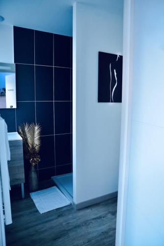 a bathroom with a blue tiled wall and a plant at L'Evasion chambre LAOS avec Jacuzzi privatif in Prinquiau