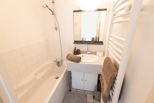 une salle de bain blanche avec un lavabo et une baignoire dans l'établissement Appart' Cosy et balcon Face à l'Océan par Groom*, à Guidel