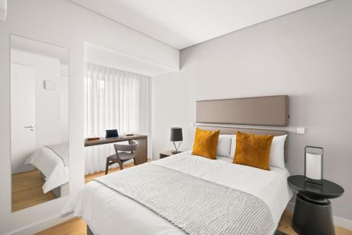 a white bedroom with a bed and a desk at Mirabilis Apartments - AAA23 in Lisbon