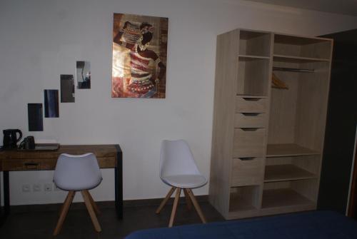 escritorio y 2 sillas junto a una estantería de madera en Chambre d’hôte Les Quatres Saisons, en La Plaine des Cafres