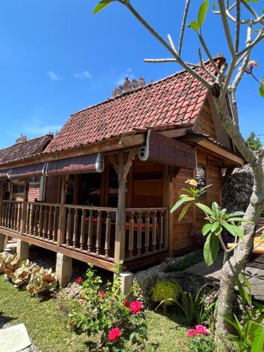 a log cabin with a deck and flowers in the yard at PINOKKIO B&B Restaurant in Jimbaran