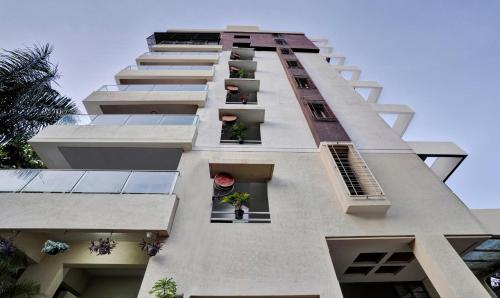 a tall white building with windows and potted plants at Treebo Trend Excellent Homes, Nashik in Nashik