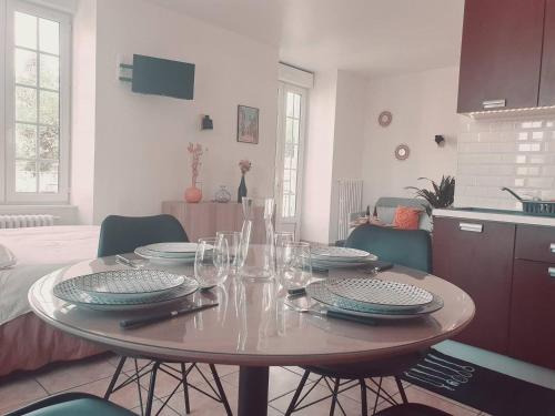 - une table à manger avec des assiettes et des verres à vin dans l'établissement Studio cocooning aux portes de DINAN PMR, à Saint-Samson-sur-Rance
