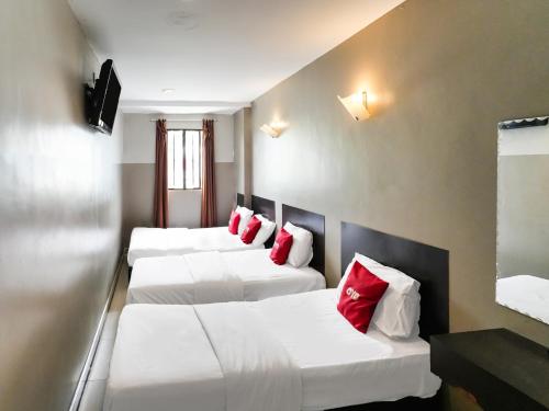 a row of three beds in a room with red pillows at OYO 89950 365 Nice Stay in Miri