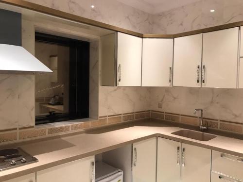 eine Küche mit weißen Schränken, einem Waschbecken und einem Spiegel in der Unterkunft VERTA Hotel in Dschidda