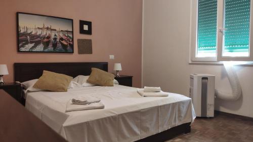 sypialnia z dużym białym łóżkiem z ręcznikami w obiekcie Airport Guest House Pisa w Pizie