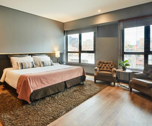 a bedroom with a large bed and a chair at Nico Apartasuites in Bogotá