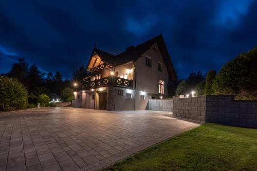 a large house with a driveway at night at Dom na wzgórzu z widokiem na jezioro z balią i sauną in Lipnica