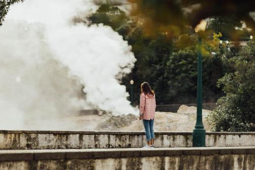a woman standing on a wall with a steam explosion at Octant Furnas in Furnas