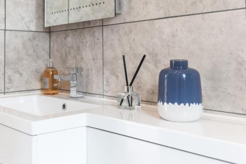 a white sink with a blue vase on top of it at Apartment in the Countryside with Hot Tub in Trowbridge