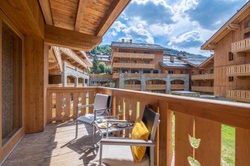 a balcony with chairs and a view of the mountains at Résidence Pierre & Vacances Premium L'Hévana in Méribel