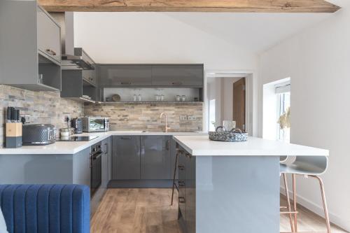 a kitchen with gray cabinets and a blue couch at Apartment in the Countryside with Hot Tub in Trowbridge