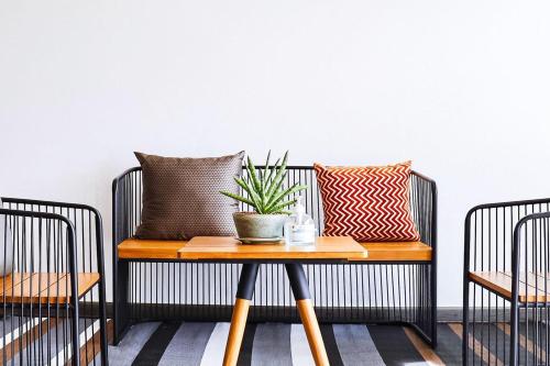 a bench with pillows and a plant on a table at Ananzitra Hotel in Kanchanaburi