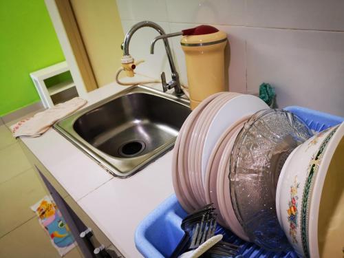 a kitchen counter with a sink and dishes at Apartment Homestay SA in Kota Bharu