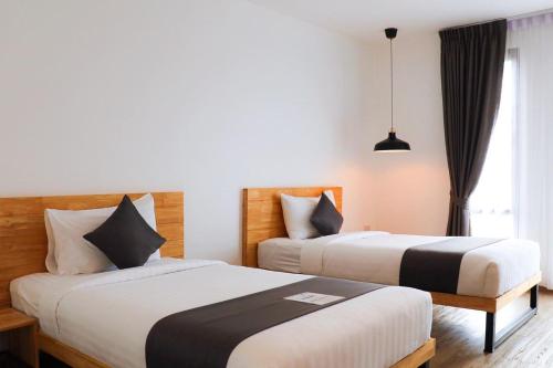 a hotel room with two beds and a window at Ananzitra Hotel in Kanchanaburi