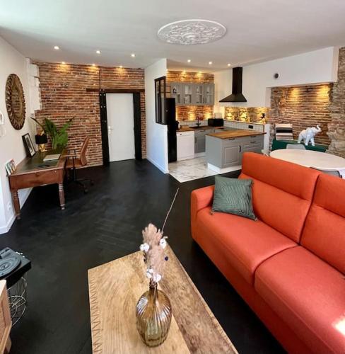 紹萊的住宿－La bâtisse de Manel，一间带橙色沙发的客厅和一间厨房