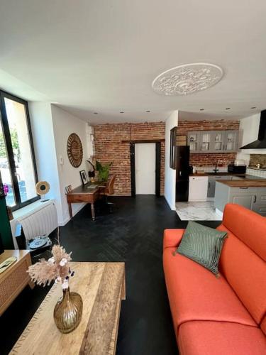un salon avec un canapé orange et une cuisine dans l'établissement La bâtisse de Manel, à Cholet