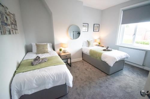 a bedroom with two beds and a mirror at Ideal Lodgings in Royton in Royton